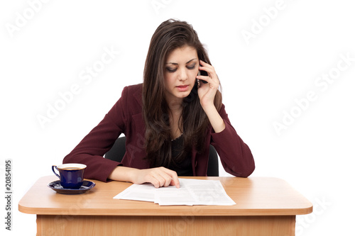 Young businesswoman speaking on phone while reading documents