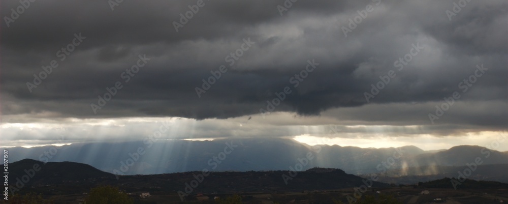 Fototapeta premium Sun beams bursting through very dark threatening clouds