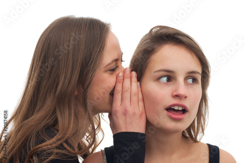 Teenage girl whispering a secret to her friend