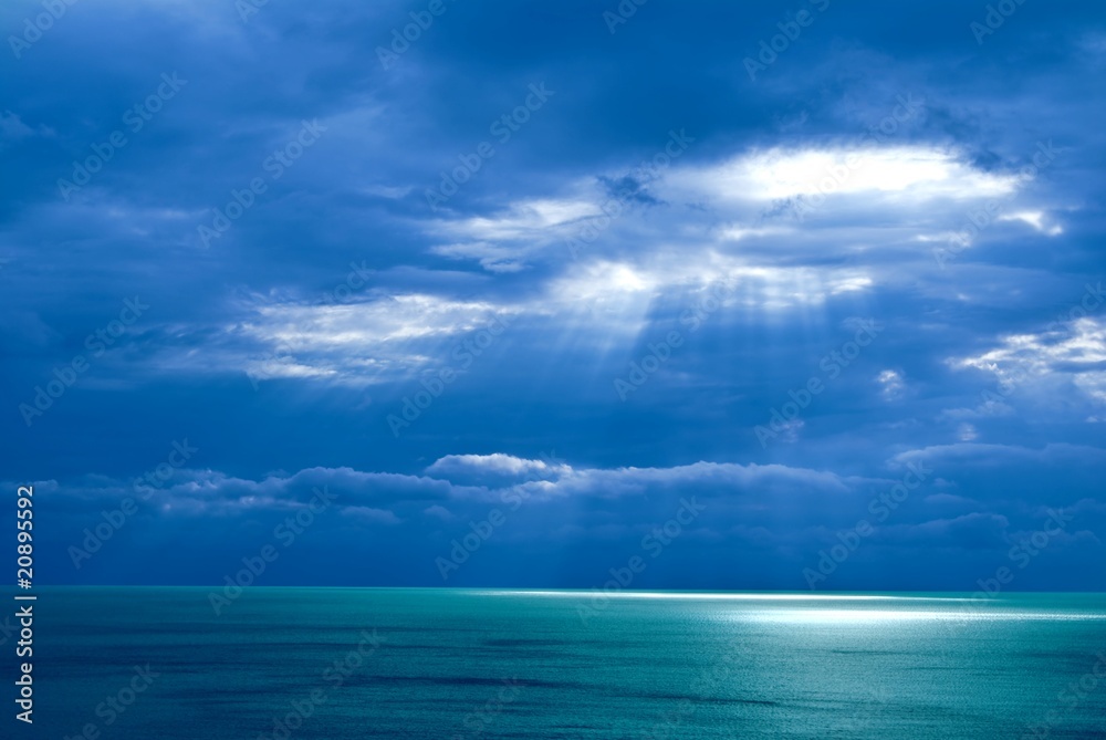 sunlight pushing through a clouds above a sea