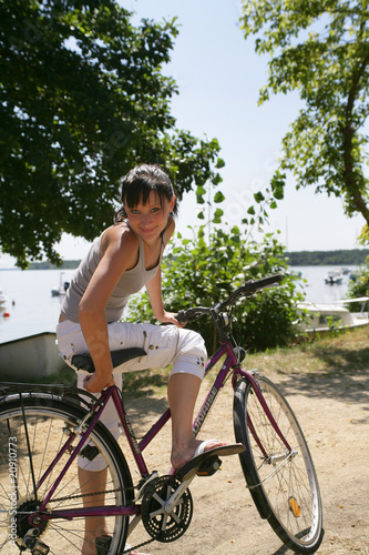 Jeune femme sourinante assise sur un vélo