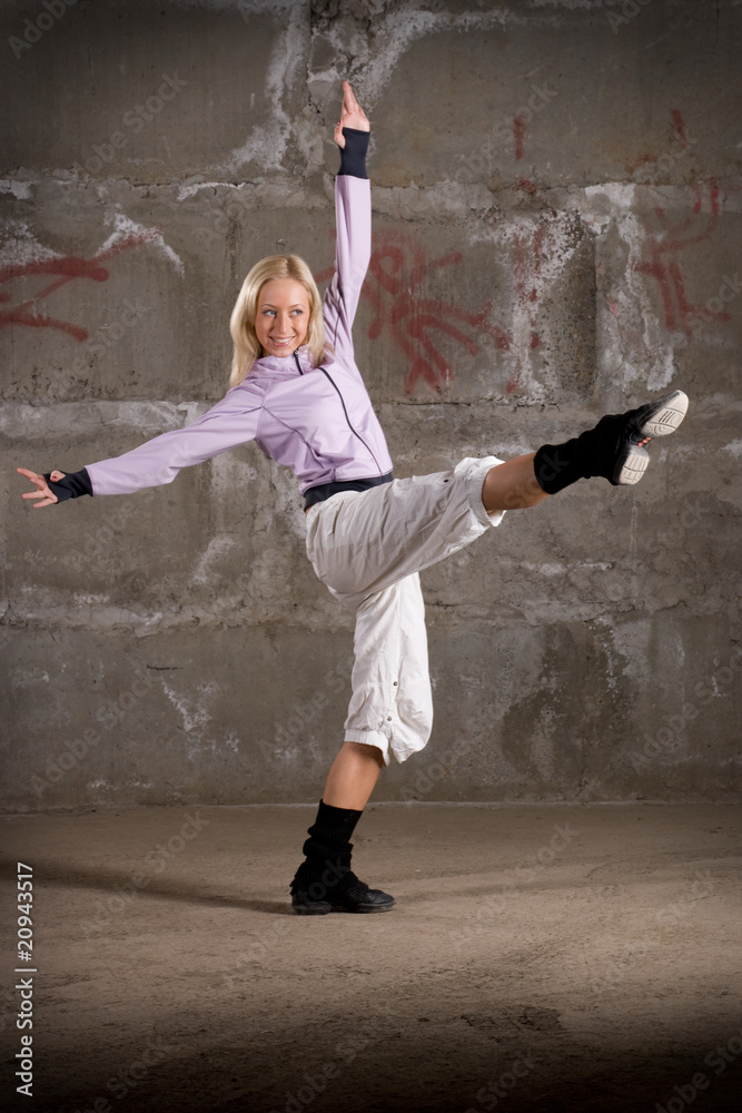 Fototapeta premium Beautiful hip hop girl dancing over grey brick wall