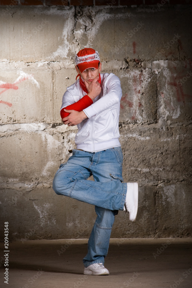 Hip hop boy dancing in modern style over grey brick wall