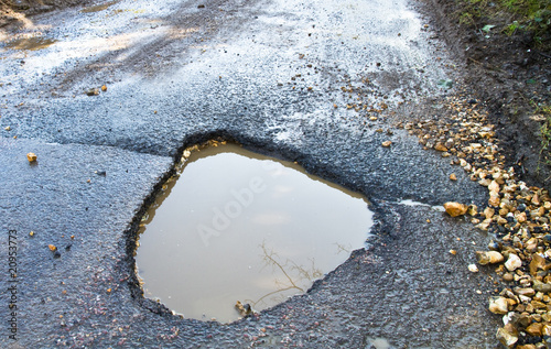 Deep, waterfilled pothole in the road