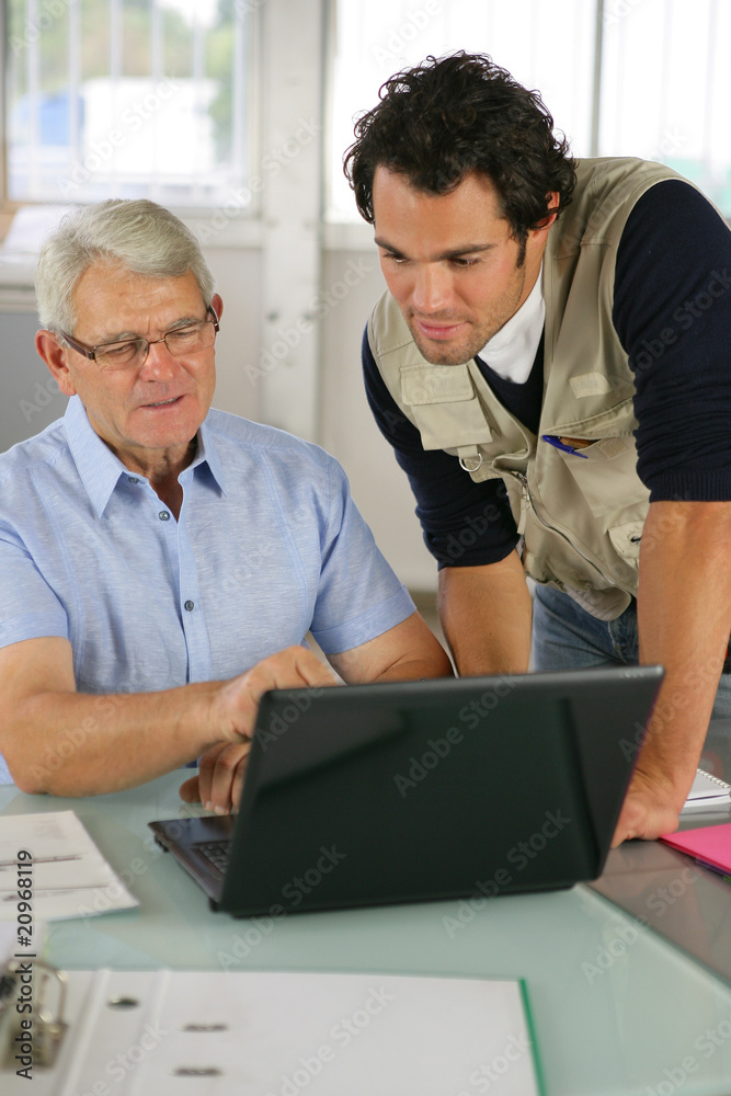 Portrait de deux hommes au bureau devant un ordinateur portable Portrait de deux hommes au bureau devant un ordinateur portable