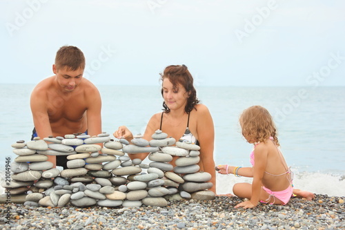 family near construction of pebbles. sea in out of focus.
