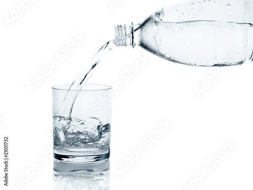 Water, flows from a plastic bottle in a glass isolated on white
