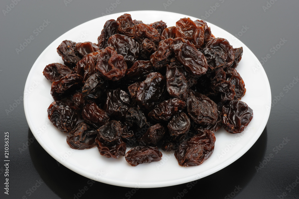 Raisin on a white plate on a black background Raisin on a white plate on a black background