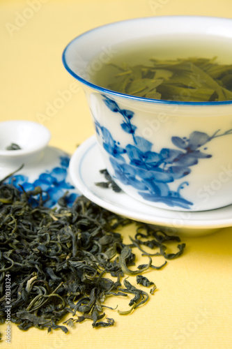 clay cup with green tea and tea leaves in dried tea leaves