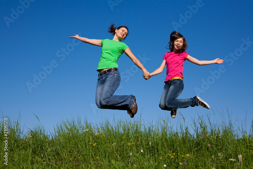 Mother and daughter jumping  running against blue sky
