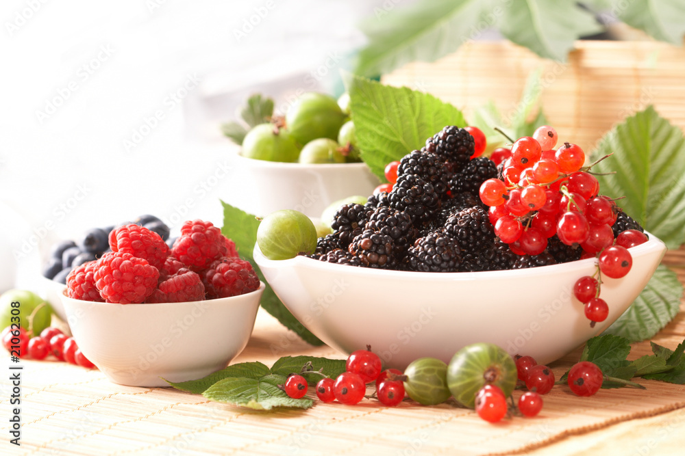 Berries in plates, on a table, among green leaves Berries in plates, on a table, among green leaves