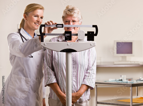 Doctor weighing senior woman in doctor office