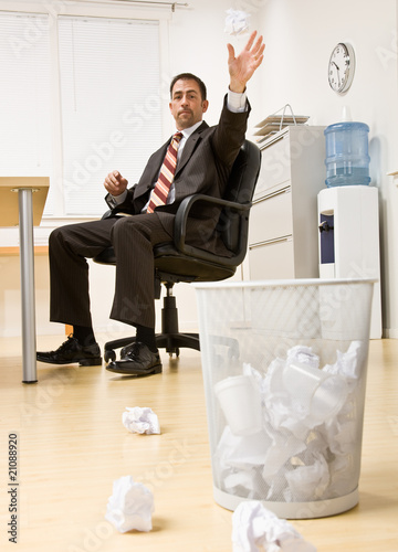 Businessman throwing paper in trash basket