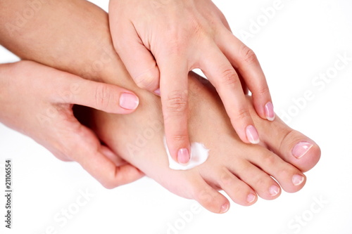 Young woman applies cream on her foot