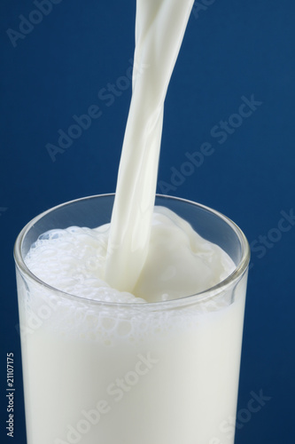Milk steaming into the glass on a blue background