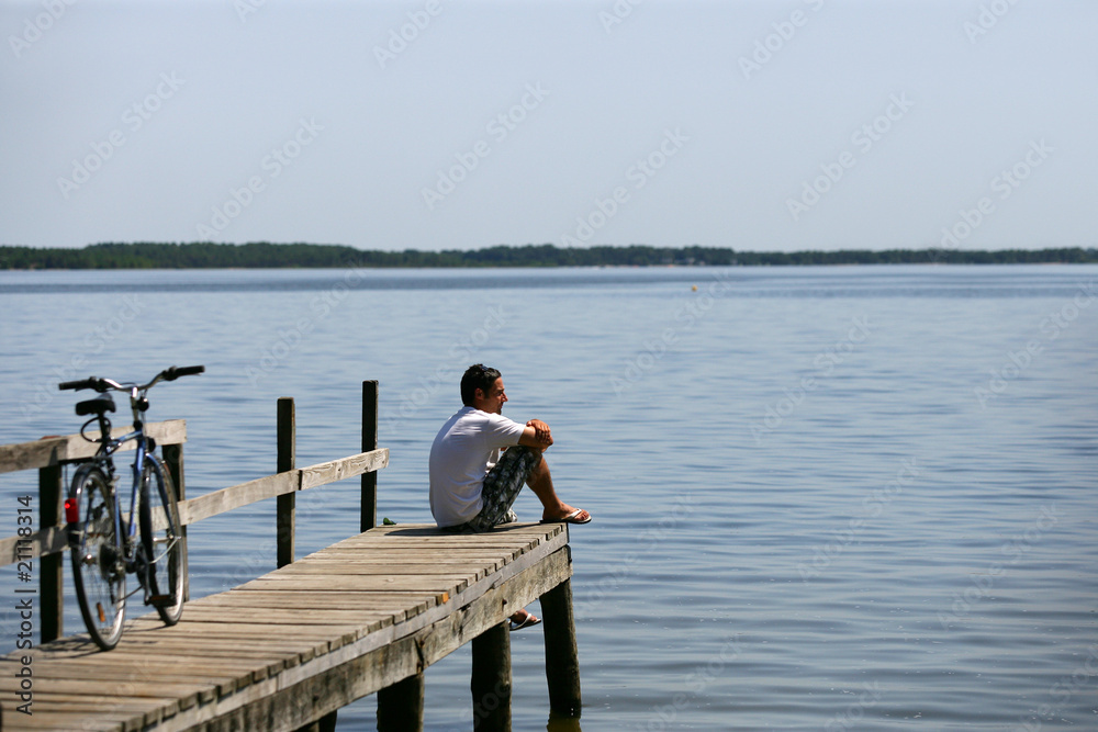 Homme assis au bord d'un lac