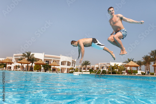 Two men jumping in swimming pool