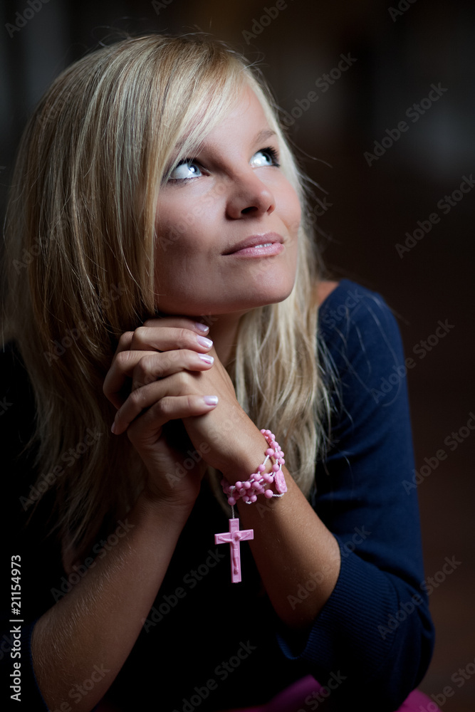Beautiful young woman with a rosary/prayer beads praying to God.