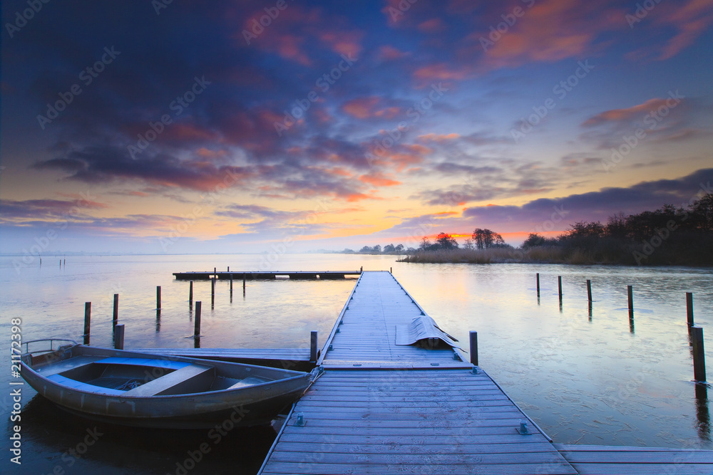 Fototapeta premium Peaceful sunrise with dramatic sky and boats and a jetty