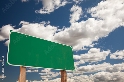 Fototapeta Blank Green Road Sign Over Clouds with Text Room