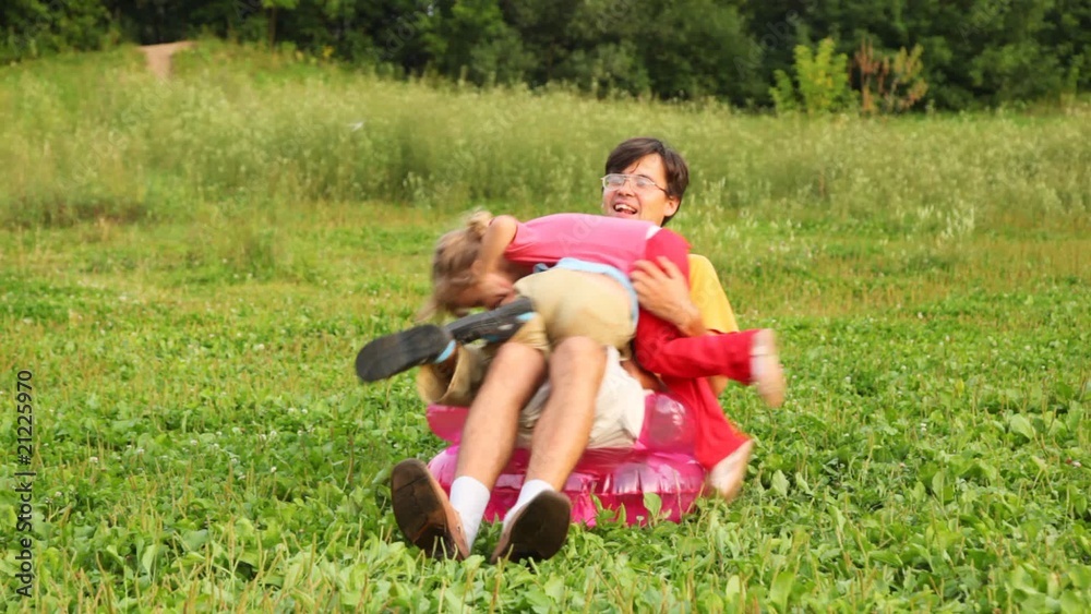 man, boy and girl sit in inflatable armchair on field and play man, boy and girl sit in inflatable armchair on field and play