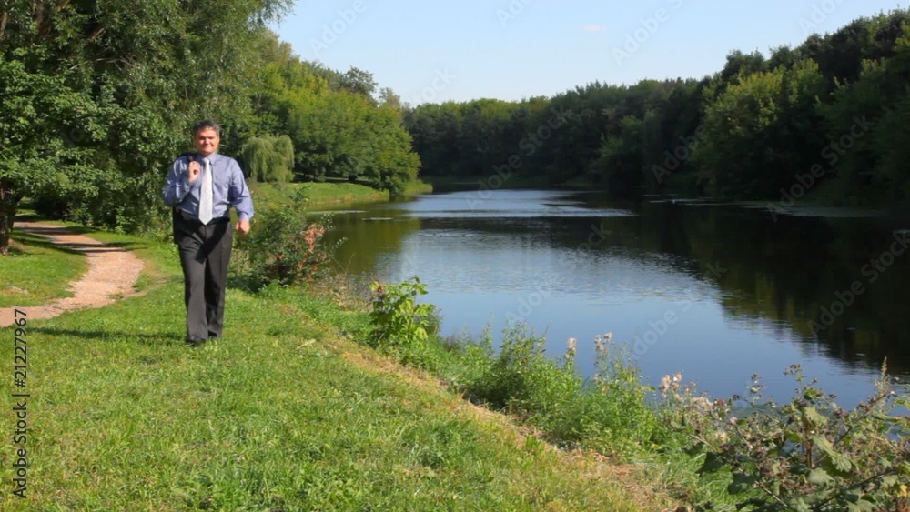 handsome man walking along bank to camera handsome man walking along bank to camera