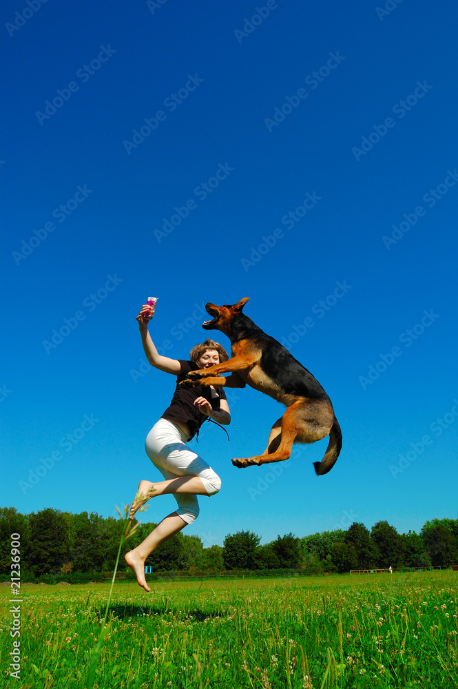 Happy girl jumping with dog against blue sky Happy girl jumping with dog against blue sky