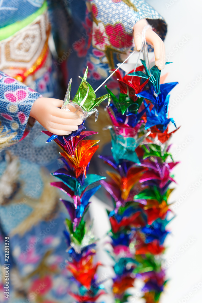 A Japanese doll in kimono arranging parts of a Senbazuru