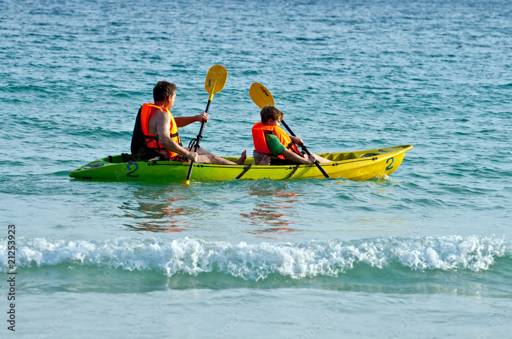 father and son are padelling with a canoe on open sea