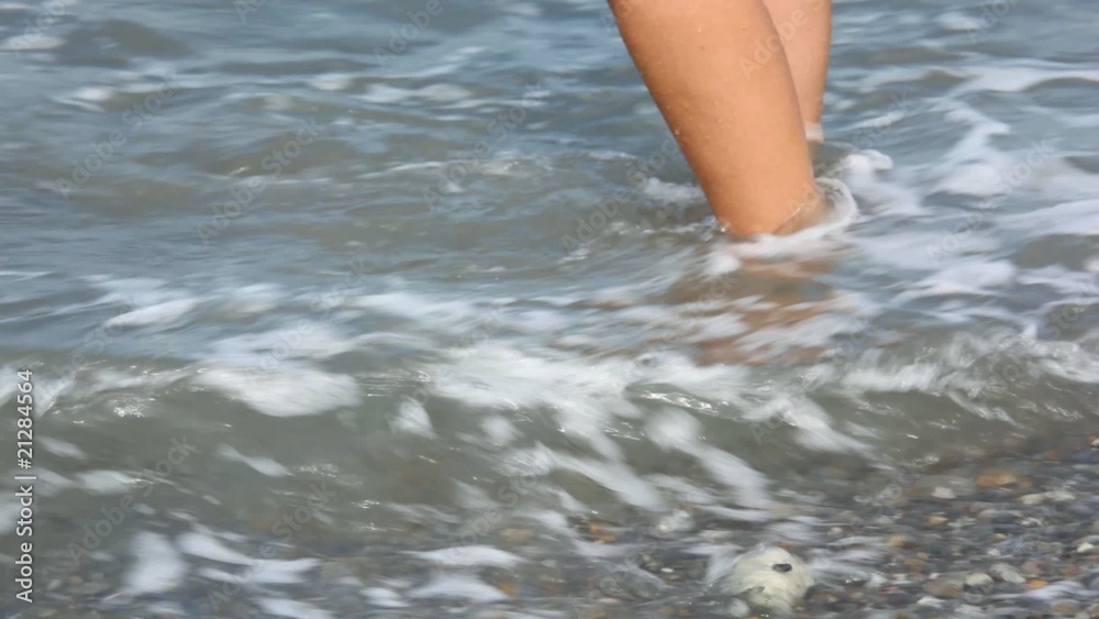 female feet with pedicure on rocky beach with sea surf female feet with pedicure on rocky beach with sea surf