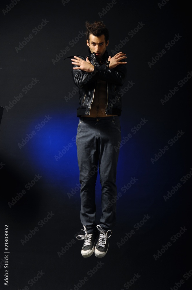 young man style jumping posing on blue light background