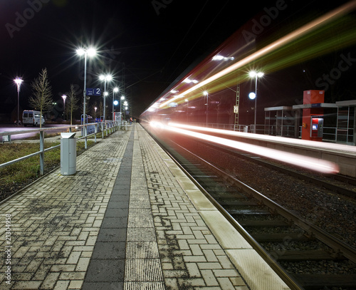 Langzeitbelichtung bei Nacht von einem Zug am Bahnhof