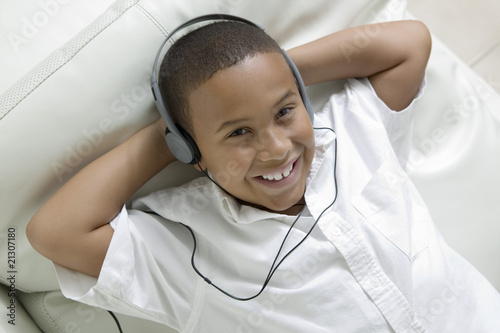 boy lying on sofa listening to music on headphones portrait overhead view