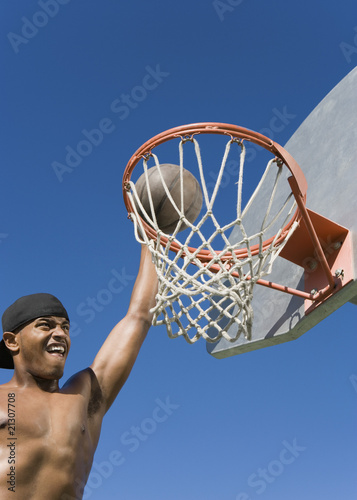 young man dunking basketball into hoop