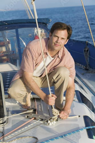man standing on sailboat tying rope (portrait)