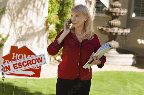 Real Estate Agent Using Cell Phone at House in Escrow photo