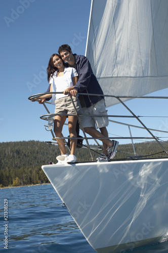 young couple standing on bow of sailboat