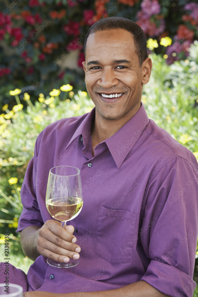 middle aged sitting holding wine glass outdoors