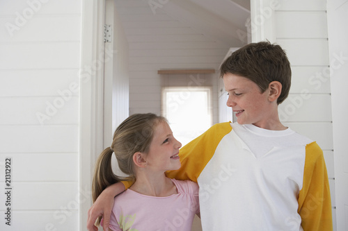 young boy with arm around girl standing in house half length