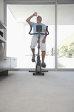 mature man on exercise bike pedalling drinking bottle of water