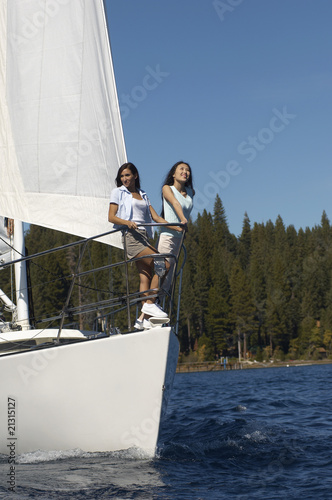 two young women standing on bow of sailboat