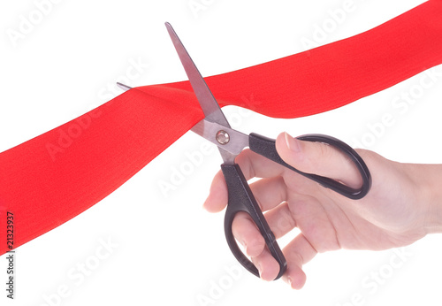 Hand with scissors cutting red ribbon