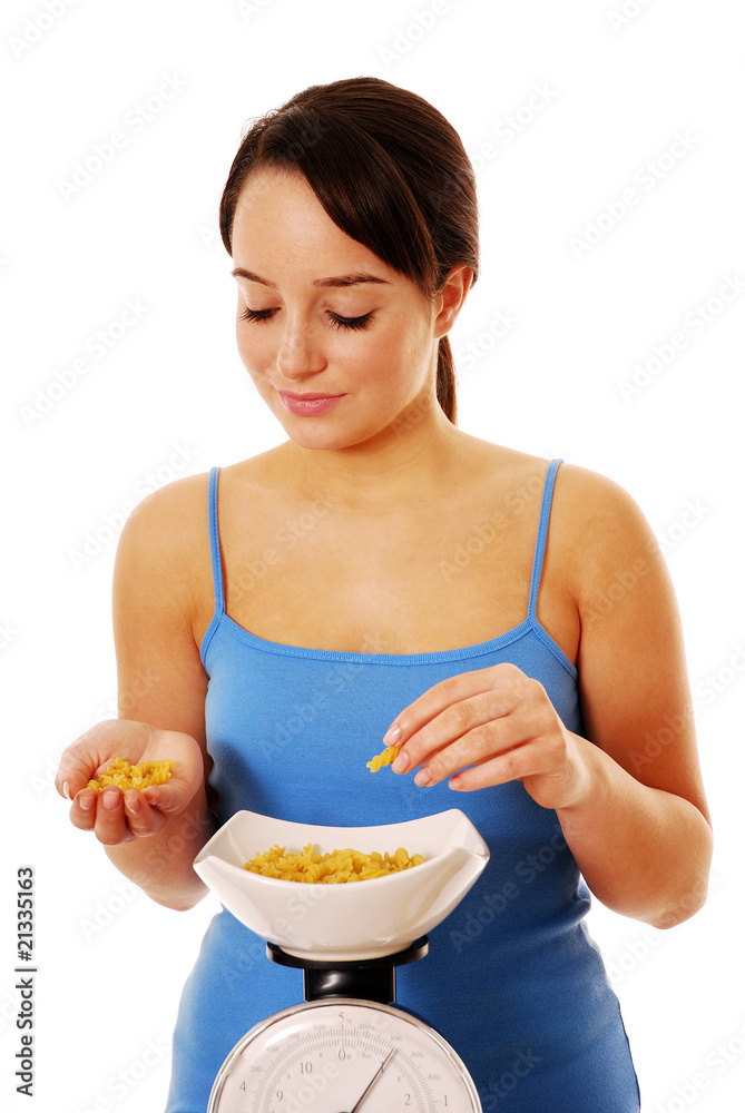 Woman weighing pasta on kitchen scales Woman weighing pasta on kitchen scales