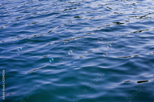 Mehrere schillernde Seifenblasen schweben über kaltes Wasser