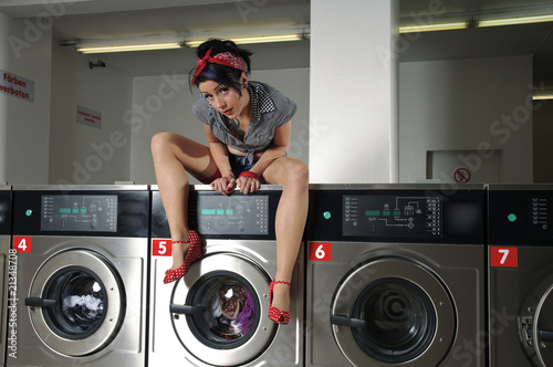 Sexy Frau im Waschsalon sitzt auf Waschmaschine photo