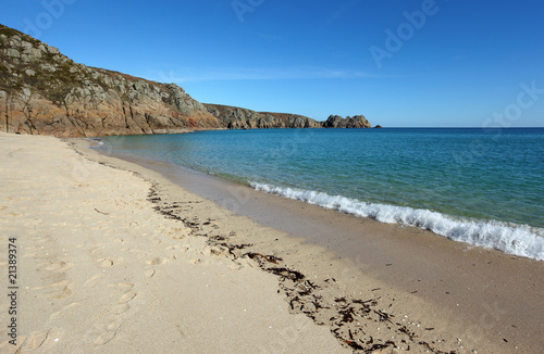 Porthcurno sandy beach shore line and Logan rock in Cornwall UK.