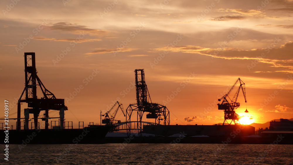 port de commerce avec un coucher de soleil et des grues
