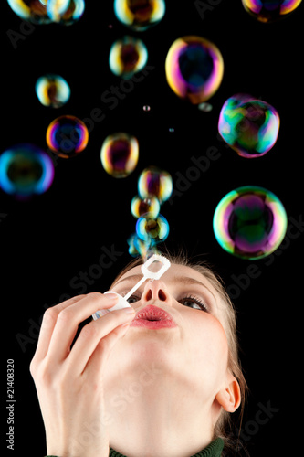 beautiful blonde girl making colorful soap bubbles