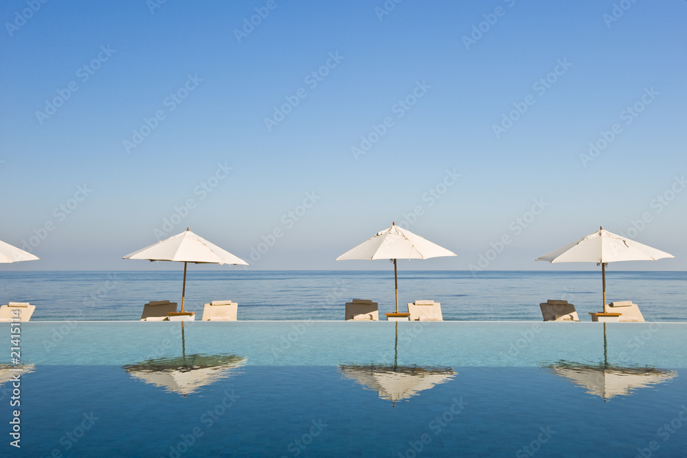 Deck chair and umbrella next to infinity pool