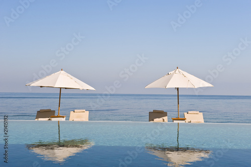 Deck chair and umbrella next to infinity pool